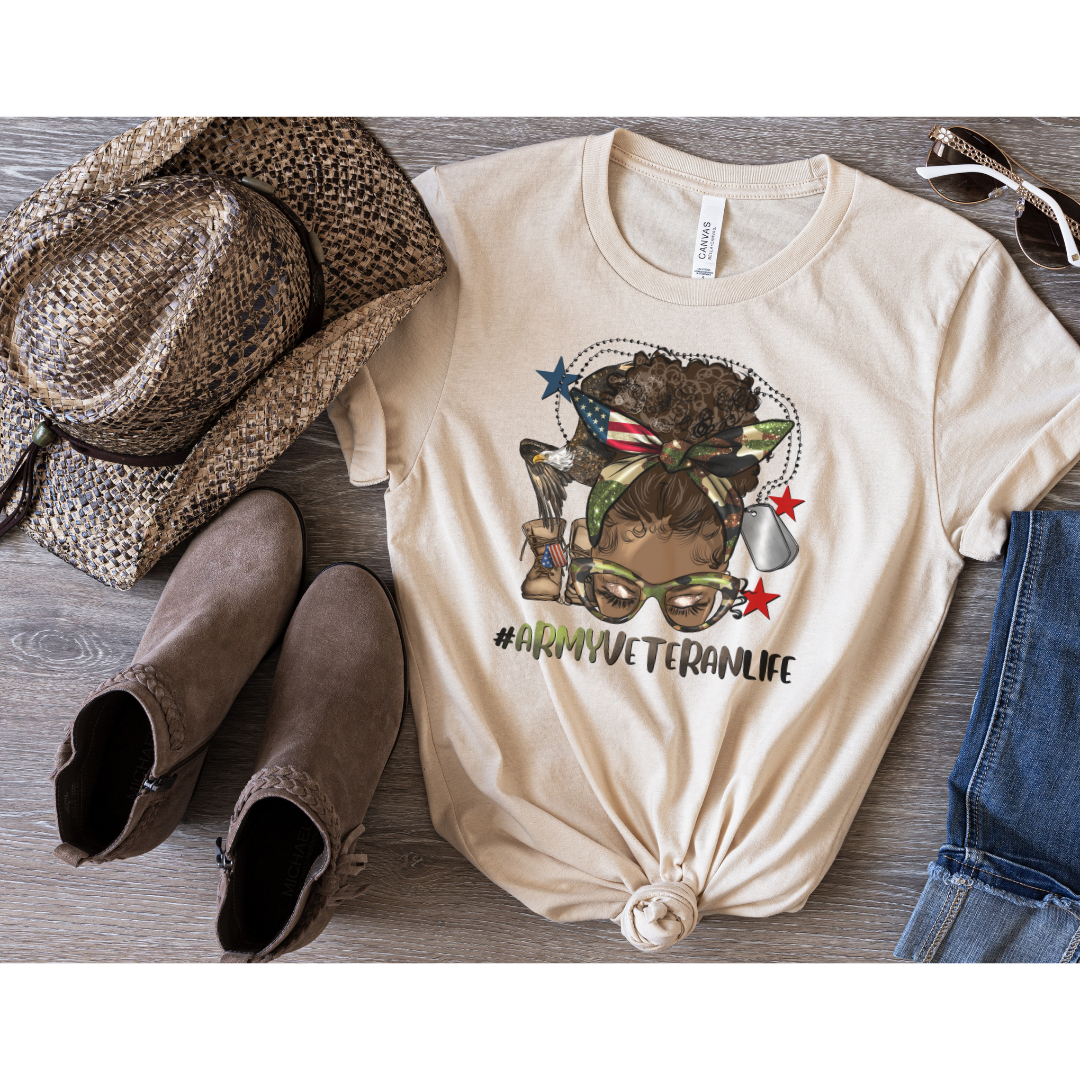 soft cream bella canvas shirt with an african american woman with a messy afro bun on the front. Under the picture it says #armyveteranlife. Dog tags and combat boots are in the background of the picture